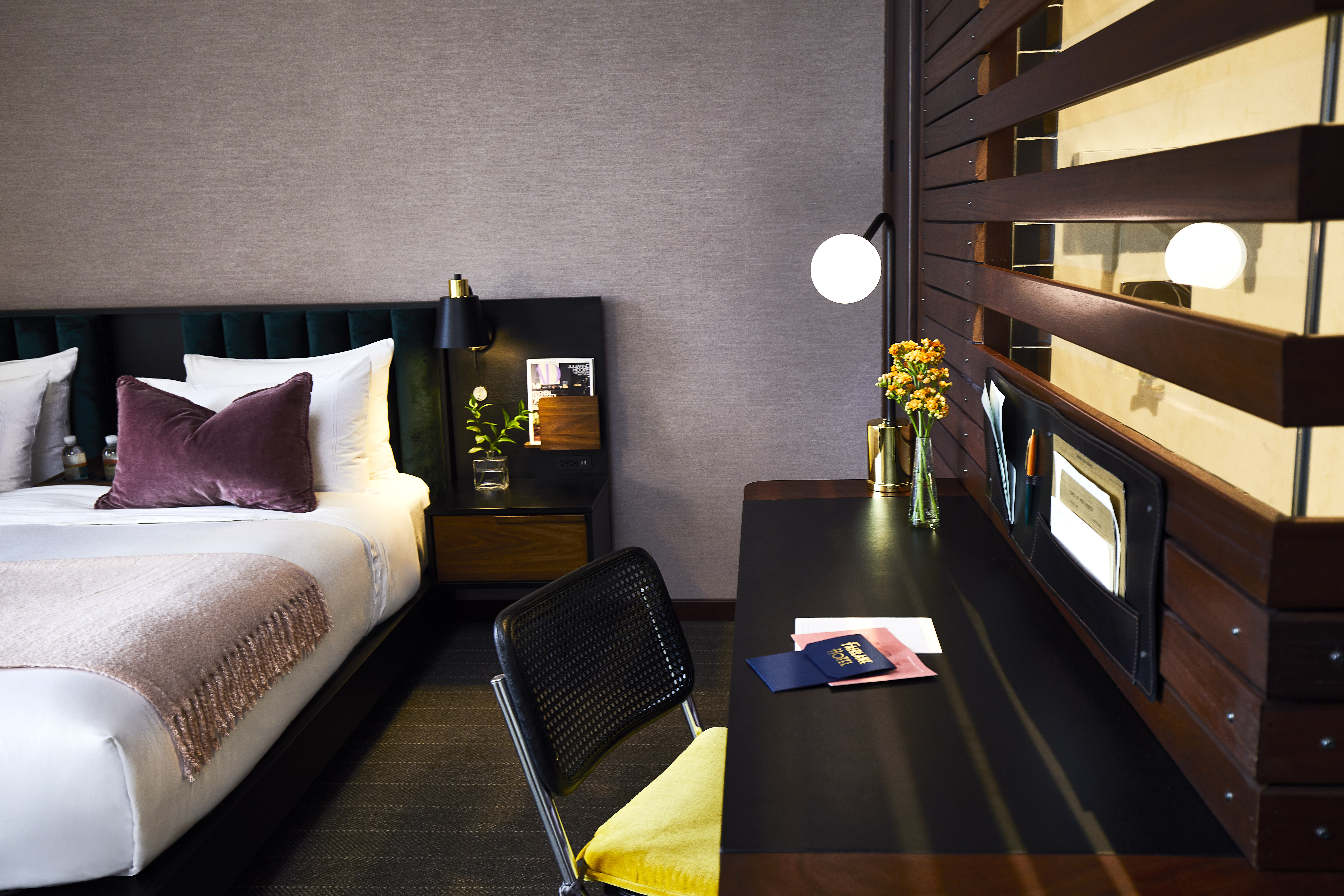 A hotel room with a bed, desk, chair, and TV.